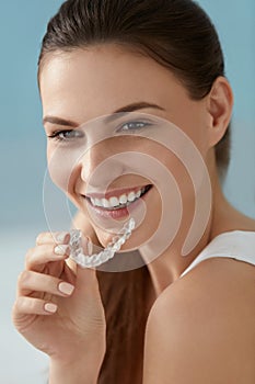 Dental care. Smiling woman using removable clear teeth braces photo