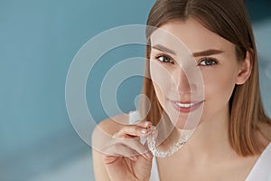 Dental care. Smiling woman using removable clear teeth braces