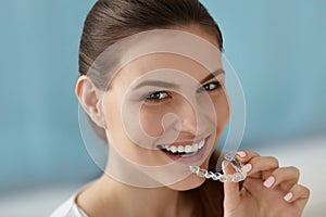 Dental care. Smiling woman using removable clear teeth braces photo