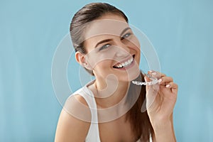 Dental care. Smiling woman using removable clear teeth braces photo