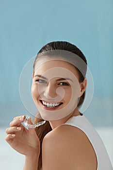 Dental care. Smiling woman with white smile using whitening tray photo