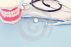 Dental care tools use for dentist and plastic teeth model in the clinic. Wooden blue background.