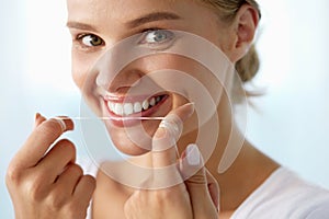 Dental Care. Woman With Beautiful Smile Using Floss For Teeth photo