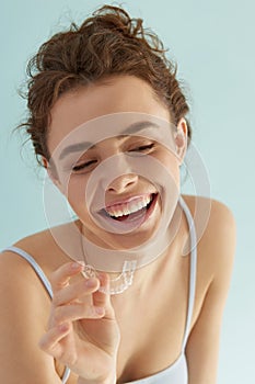 Dental care. Woman with toothy smile holding silicone brace