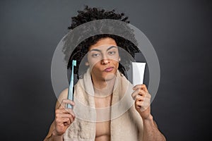 Young guy holding tooth brush and toothpaste and looking uncertain photo