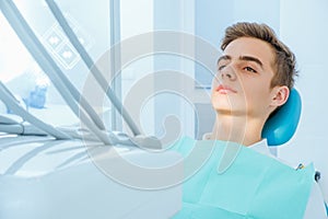 Dental caries prevention.Teenage boy at the dentist`s chair during a dental procedure, smile close up. Healthy Smile.