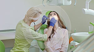 Dental caries treatment in dental office. Woman with open mouth in dentist chair