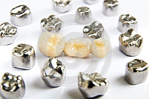Dental ceramic, gold and metal tooth crowns on white background.