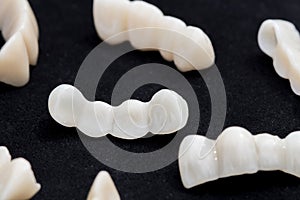 Dental ceramic or zirconium tooth bridges on dark black surface. photo