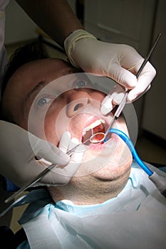 Dental check up. Dental checkup with dental tools probe, mirror and suction tube in mouth. Dentist is examining of patient teeth.
