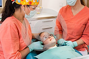 Dental checkup, being given to young girl, by female dentist with assistant