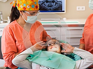 Dental checkup, being given to young girl, by female dentist with assistant