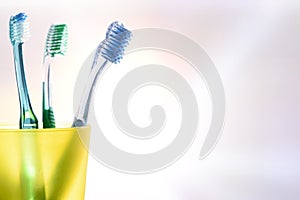 Daily dental cleaning with yellow plastic cup with toothbrushes detail