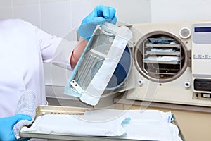 A dental clinic employee holds sterilized instruments in a sealed bag. An unrecognizable photo. Copy of the space