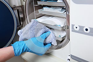 A dental clinic employee removes sterilized instruments from a dry firing cabinet. The concept of sterility and hygiene in the