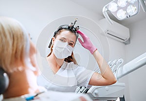 Dental clinic patient appointment in modern medical ward. Dentist doctor in magnifying glasses smiling with eyes young Female