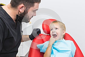 Dental clinic. Reception, examination of the patient. Teeth care. Dentist treating teeth of little boy in dentist office