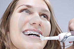 Dental Concept and Ideas. Extreme Closeup Portrait of Caucasian Teenage Girl Brushing Teeth Brackets with Electric Toothbrush