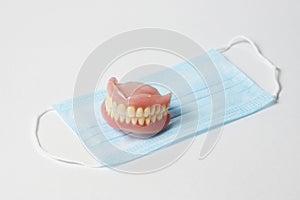 Dental dentures and medical mask on white background