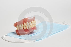 Dental dentures and medical mask on white background