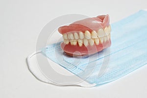 Dental dentures and medical mask on white background