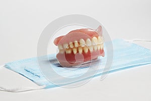 Dental dentures and medical mask on white background