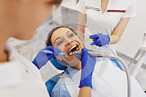 Dental doctor and nurse using tools to treat woman teeth