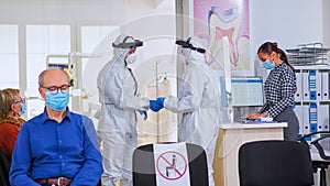 Dental doctors with protection suit analysing teeth x-ray in reception