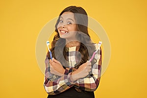 Dental excellence. Happy child hold brushes on yellow background. Small girl happy smile with toothbrushes. Dental