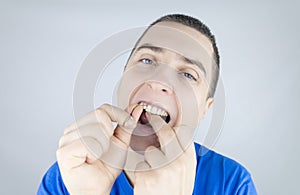 Dental floss close up. A man in front of a mirror brushes his teeth with flossing. The concept of proper oral care. Selective