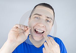 Dental floss close up. A man in front of a mirror brushes his teeth with flossing. The concept of proper oral care. Selective