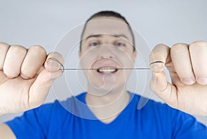 Dental floss close up. A man in front of a mirror brushes his teeth with flossing. The concept of proper oral care. Selective