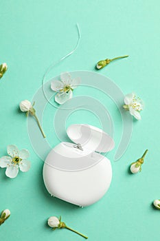 Dental floss and flowers on mint background