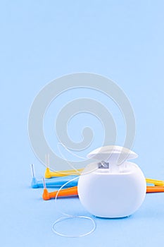 Dental floss and interdental brush angles on blue background, vertical, copy space