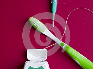 Dental floss, interdental brush and toothbrush on red background