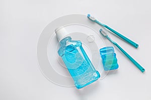 Dental floss with tooth brushes and rinse on white background