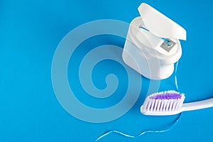 Dental floss and toothbrush on a blue background, the concept of care for the oral cavity