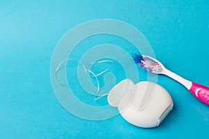 Dental floss and toothbrush on blue background.Personal dental hygiene accessories