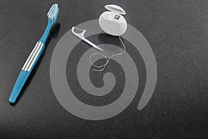 Dental floss and toothbrush on gray background