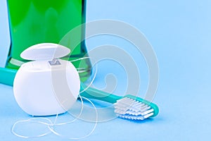Dental floss, toothbrush and mouthwash on blue background. Tooth care and oral hygiene products