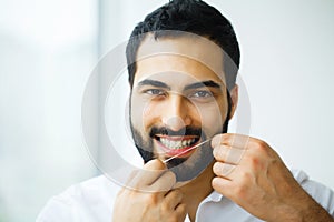 Dental Health. Man With Beautiful Smile Flossing Healthy Teeth.