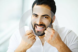 Dental Health. Man With Beautiful Smile Flossing Healthy Teeth. photo