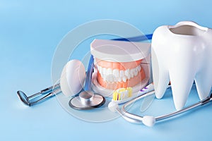 Dental health and teethcare concept. Dental mirror with explorer probe, toothbrush, floss, human jaw model and white tooth with