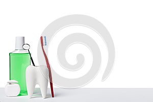 Dental health and teethcare concept. Dental mirror in white tooth model near mouthwash, toothbrush and dental floss against white