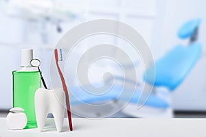 Dental health and teethcare concept. Dental mirror in white tooth model near mouthwash, toothbrush and dental floss against dental