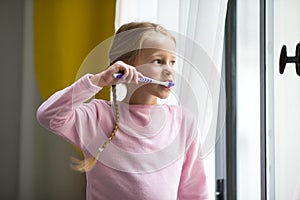 Dental hygiene. Happy little girl brushing her teeth indoor