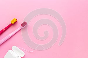 Dental hygiene - tooth brushes, dental floss flat lay, top view, copy space, pink background