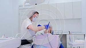 Dental hygienist cleaning and brushing woman's teeth uses drill with brush.