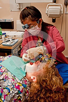 Dental hygienist cleaning patient's teeth photo