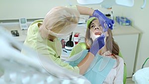 Dental hygienist examining patient teeth with mouth mirror and dental probe